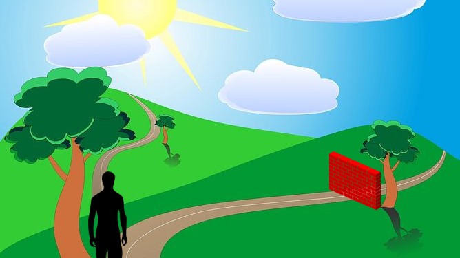 Man at a fork  in the road. One road has brick wall, one is clear.