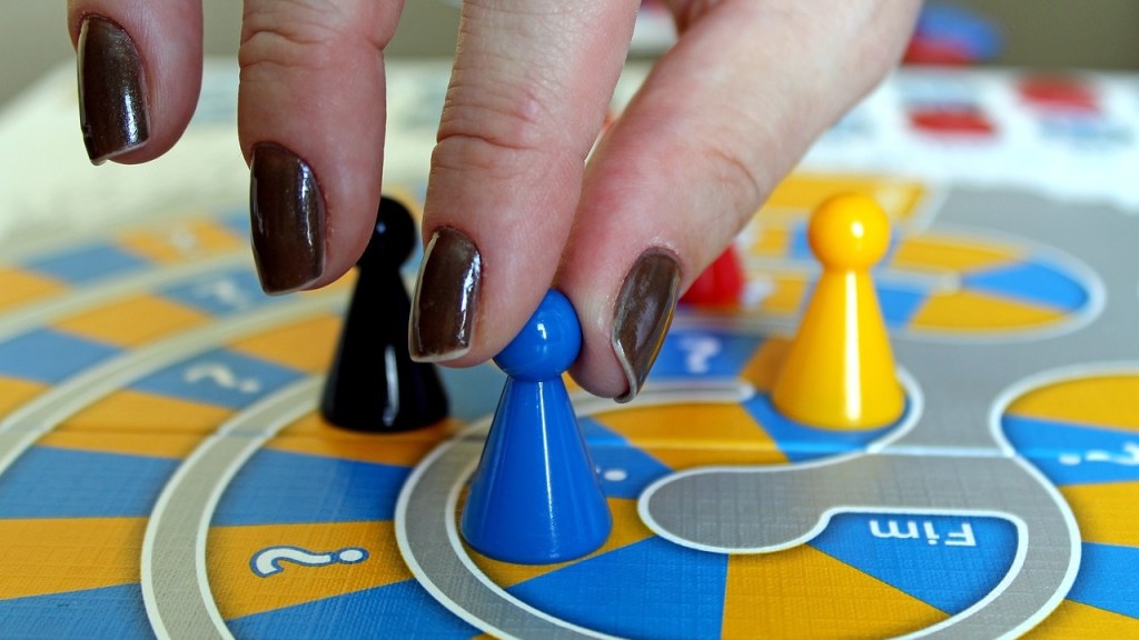 close-up on hand moving playing piece on a board game.