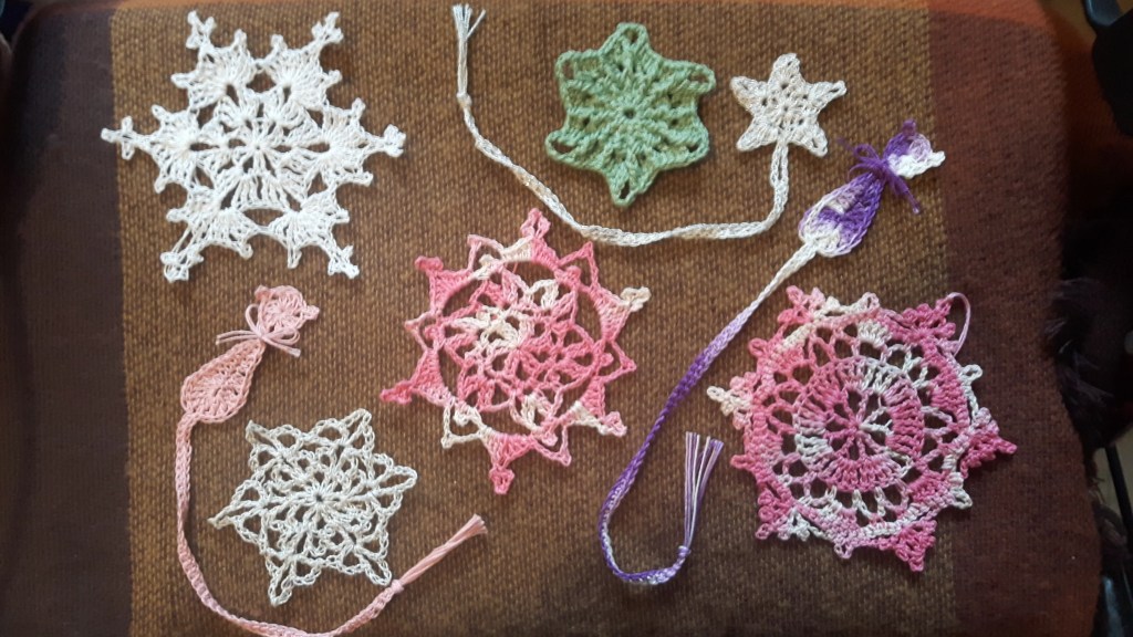 A picture of 5 crocheted snowflakes as well as 2 cat bookmarks and a star bookmark.
