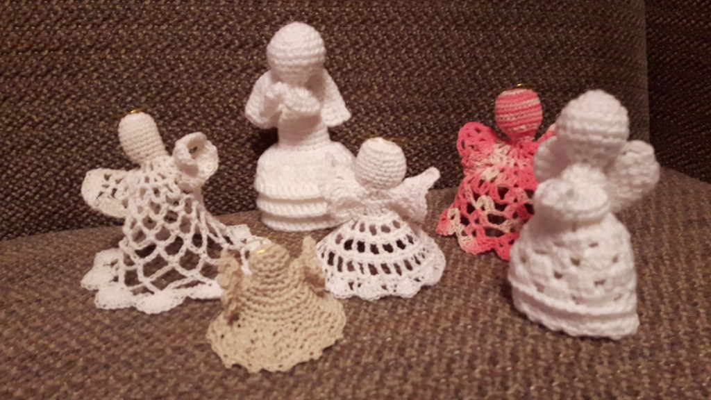 A picture of 6 crocheted angels, each a different design. 4 white, one pink and one beige.